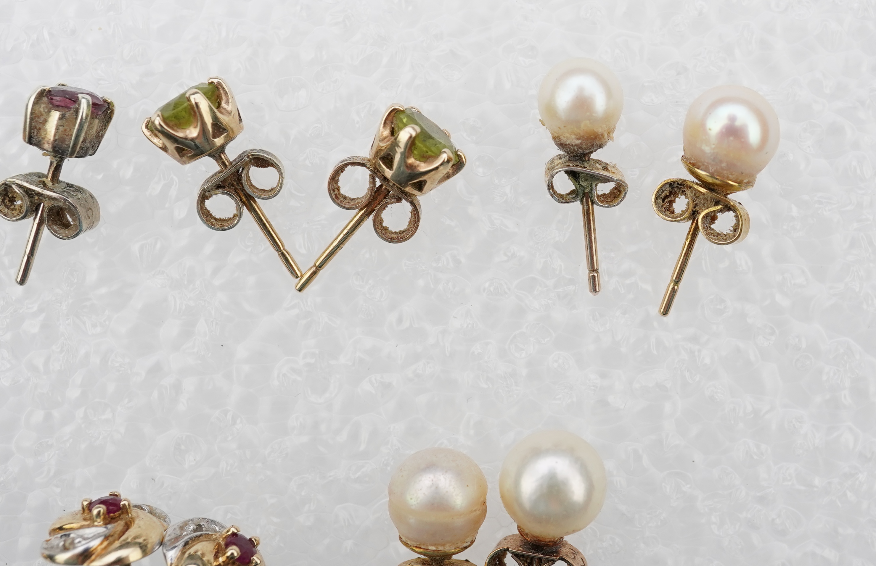 Four assorted pairs of 9ct and gem set ear studs including peridot and cultured pearl, together with three other assorted pairs yellow or white metal ear studs and two odd ear studs.